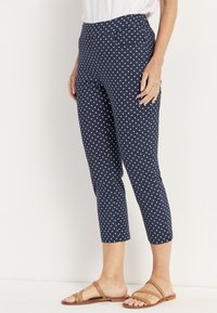 Marina blå leggings i elastiskt tyg, med ett vitt prickmönster, hög midja och kort längd.