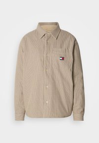 Gombos ing bézs kockás mintával, foltzsebbel és logó részlettel. Gallérral és gombos lezárással rendelkezik. Hosszú ujjú.