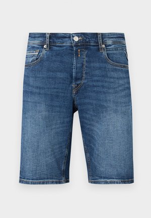 Pánske stredne modré rifľové šortky s predným gombíkom, zipsom, slučkami na opasok a päťvreckovým strihom na jednofarebnom pozadí.