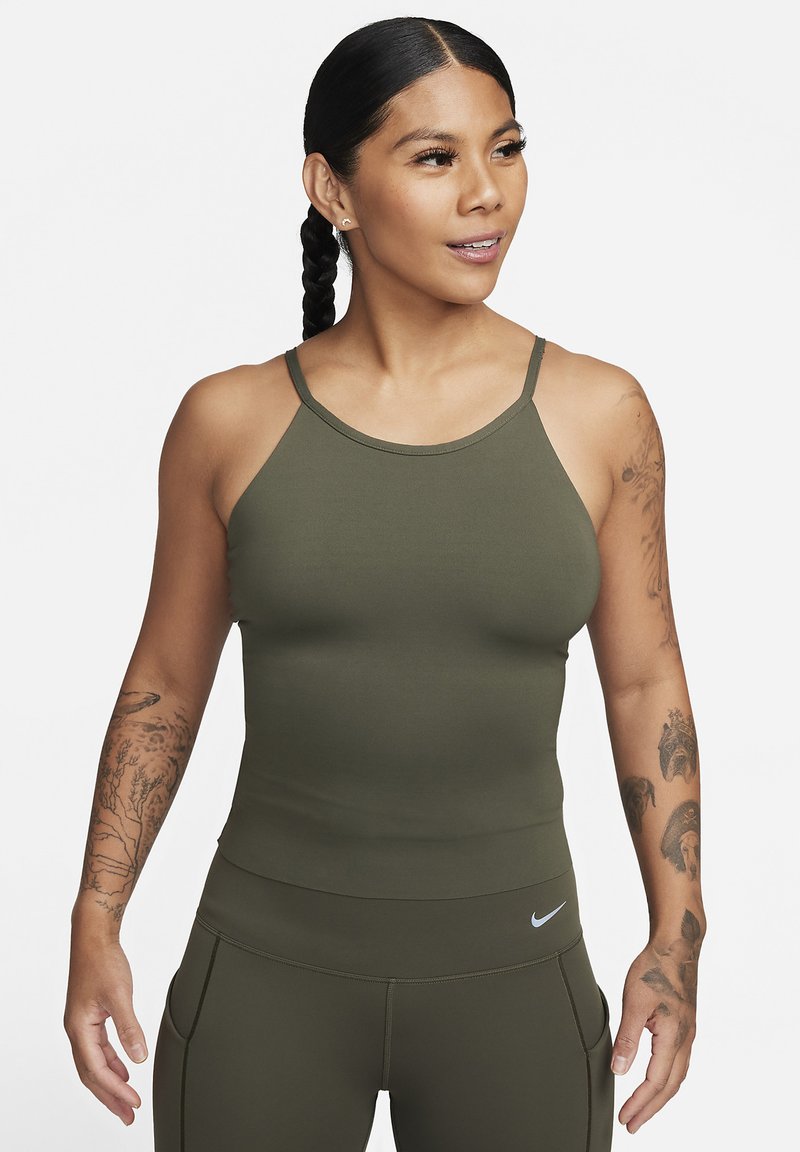 Canottiera atletica attillata di colore verde oliva con spalline sottili e scollatura rotonda. Texture liscia, abbinata a leggings coordinati con un logo.