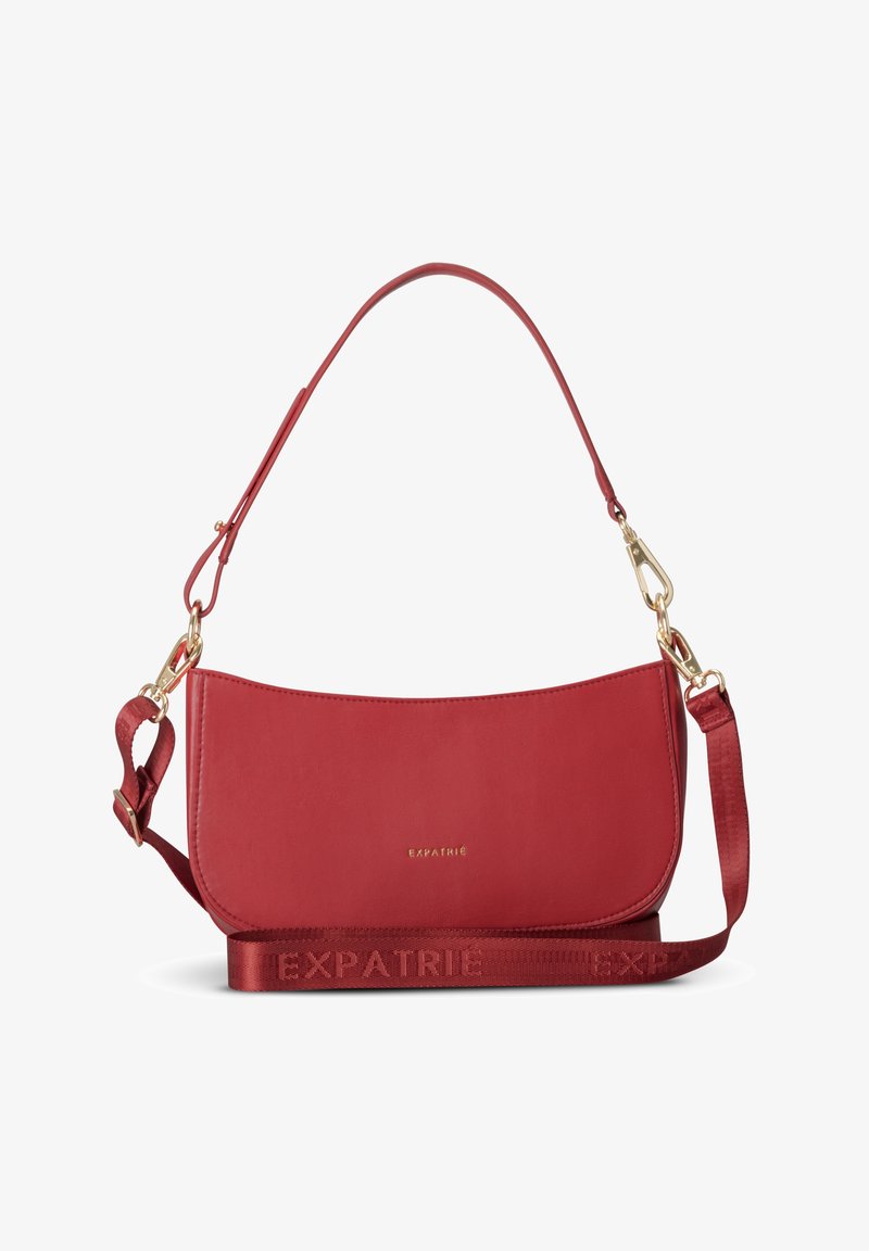 Sac à bandoulière en cuir rouge avec fermoirs dorés, sangle réglable et nom de marque gravé "Expatrié" au centre avant.