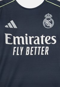 Maillot de sport bleu marine en texture côtelée, arborant le texte blanc "Emirates Fly Better", le logo Adidas et le blason du Real Madrid. Encolure ronde.