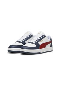 Zapatillas blancas, marinas y rojas con un upper de cuero liso, punta perforada y cuello acolchado. Presenta el logo de PUMA y suela de goma.
