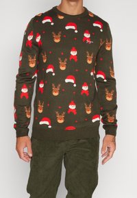 Grön stickad tröja med ett festligt mönster av jultomtar och renar, accentuerad med röda och vita mössor. Ribbat vid ärmarna och nederkanten.