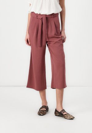 Rose-colored culottes with a tie belt, soft fabric, loose fit, and pleated details, paired with leopard print flats.