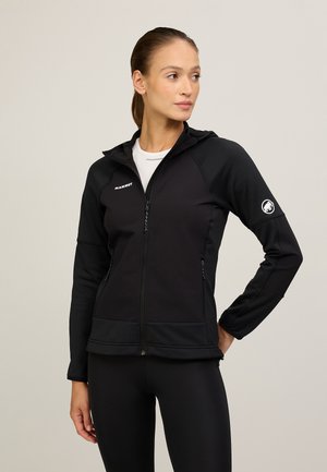 Black zip-up jacket with a textured material, fitted design, hood, and logo details. Features side pockets and a stretchy hem.