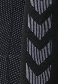 Črn material s sivimi navpičnimi vzorci ribje kosti na desni strani in tankimi vzporednimi črtami, ki tvorijo vzorec ribje kosti na levi strani.