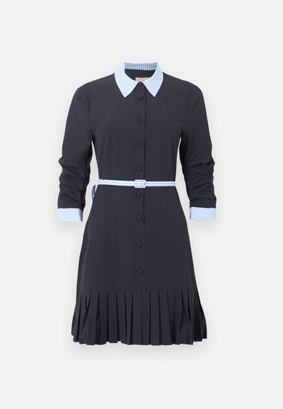 Črna obleka z dolgimi rokavi in naborki na krilu, modro-belo črtast ovratnik in manšete, pas z enakim črtastim vzorcem ter gumbi na sprednji strani.