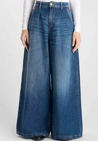 Blauwe denim jeans met wijde pijpen en een hoge taille, voorzien van een knoop- en ritssluiting, dik stof en subtiele vervaging voor textuur.