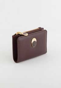 Dark burgundy leather wallet with a gold zipper and circular clasp. Features textured exterior and a compact rectangular shape.