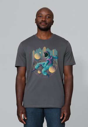 Grijze katoen t-shirt met een kleurrijke astronautafbeelding, afgewerkt met geometrische patronen en cirkels in tinten blauw, paars en geel.