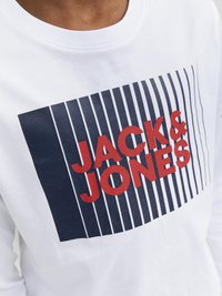 Bela dolga majica z dolgimi rokavi, ki prikazuje mornarsko modro in rdečo grafiko z besedilom "JACK & JONES", postavljeno proti navpičnim črtam. Gladek bombažen material.