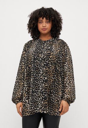 Blouse à imprimé léopard avec une coupe ample, un col rond et de longues manches bouffantes. Fabriquée en tissu léger dans des tons de noir, marron et beige.