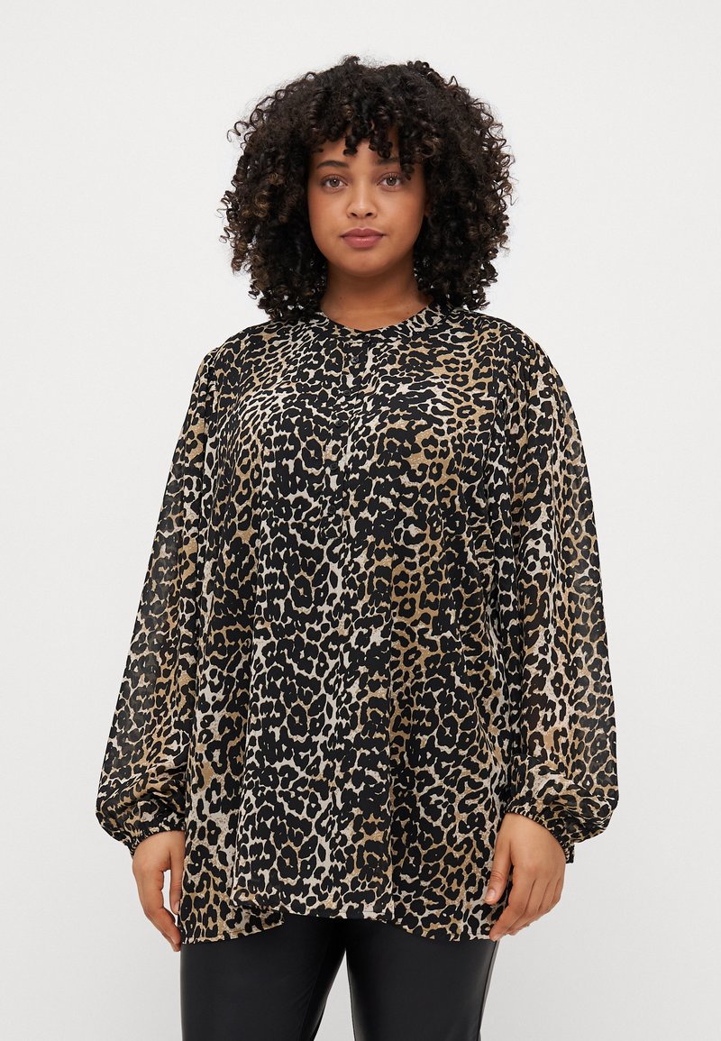 Blouse à imprimé léopard avec une coupe ample, un col rond et de longues manches bouffantes. Fabriquée en tissu léger dans des tons de noir, marron et beige.
