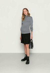 Suéter cinza de gola alta, saia preta, botas de tornozelo pretas e uma mala preta. Design simples com uma textura suave e silhueta ajustada.