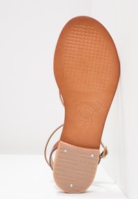Sole di sandalo in pelle marrone chiaro con un motivo testurizzato e il nome del marchio impressa. Presenta una forma arrotondata e hardware minimo. Taglia 37.