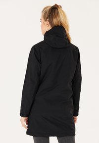 Svart vattentät parkas med huva, med långa ärmar, rak skärning och en slät textur. Justerbar huva vid halslinningen.
