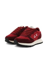 Sneaker in suede e tessuto rosso con un accento bianco, dotate di una chiusura con lacci, superficie testurizzata e branding prominente sul lato.