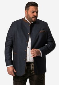 Navyblauwe wollen jas met bruine leren accenten, voorzien van ronde gouden knopen en een borstzak met een geruite zakdoek.