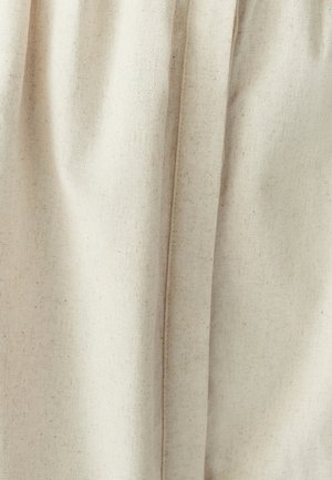 Light beige fabric with a textured finish, featuring soft, flowing drapes and subtle creases. Plain design without patterns or accents.