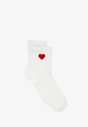 Ein Paar weiße Rippensocken mit einem kleinen roten Herz, das nahe der Oberseite auf einer Socke gestickt ist, auf einem weißen Hintergrund dargestellt.
