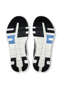 Schwarze und weiße Sohlen von Sportschuhen mit strukturierten Griffmustern und einem blauen Akzent. Enthält erhabene weiße Bereiche zur Polsterung.