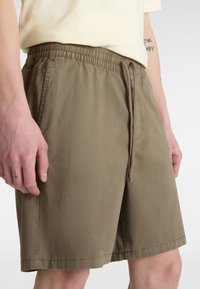 Khaki kraťasy z lehké látky. Mají elastický pas s šňůrkou, boční kapsy a volný střih.