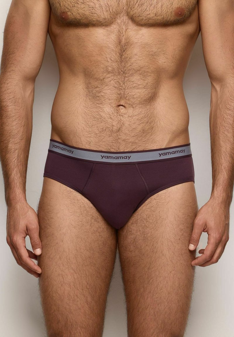 Slip da uomo in un profondo bordeaux, con una vita grigia decorata dal logo "yamamay". Tessuto morbido con un design aderente e leggermente elasticizzato.
