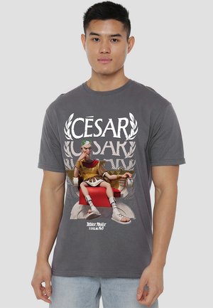 Gray cotton t-shirt featuring a cartoon character dressed in a Roman toga and armor, with bold white text reading “CÉSAR” above.
