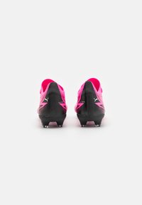 Scarpini da calcio rosa brillante con una suola nera testurizzata, caratterizzati da un design elegante e dettagli con il logo Puma sul tallone e sui lati.