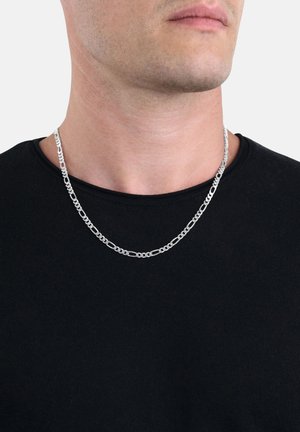 Collana in argento con anelli ovali di dimensioni alternate, indossata attorno al collo di una persona in una maglietta nera a girocollo.