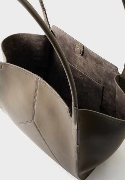 Grand sac cabas en cuir beige avec deux poignées, ouverture sur le dessus, et intérieur en suédine douce avec une poche à pression.