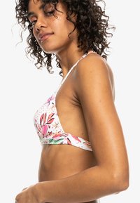 Bikini-top met bloemenprint in roze, groen en neutrale tinten. Heeft een diepe halslijn en dunne verstelbare bandjes. Soepele, rekbare stof.
