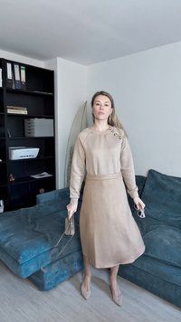 Beige mønstret genser med tre knapper på skulderen, kombinert med en kne-lengde beige skjørt og matchende hæler, holder en liten veske.