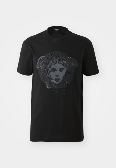 Black cotton T-shirt featuring a glossy Medusa graphic with intricate details and the "Versace" logo below, set against a smooth texture.