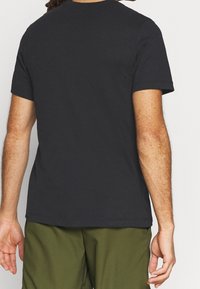 Camiseta de algodón negra con mangas cortas, cuello redondo y corte recto, que no presenta patrones ni adornos visibles.