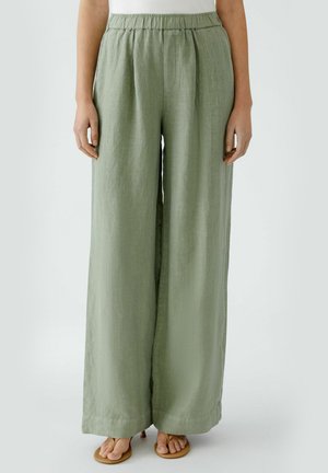 Pantalons larges vert clair en tissu texturé avec une taille élastique et des plis sur les côtés. Ourlet à la base pour une finition propre.