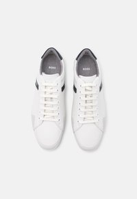 Baskets en cuir blanc présentant un design texturé, des accents bleu marine contrastants et des détails perforés. Lacets plats avec un col rembourré.