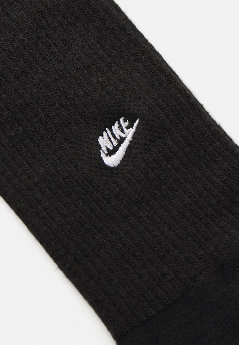 Chaussette Nike noire avec une texture côtelée, présentant un logo brodé blanc sur le côté. Matière douce et design sans couture au bout.