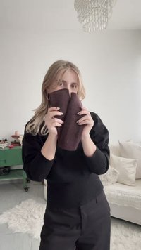 Article en tissu marron foncé tenu dans les deux mains. Texture douce, forme rectangulaire, présentant un design sans couture. Esthétique simple et minimaliste.