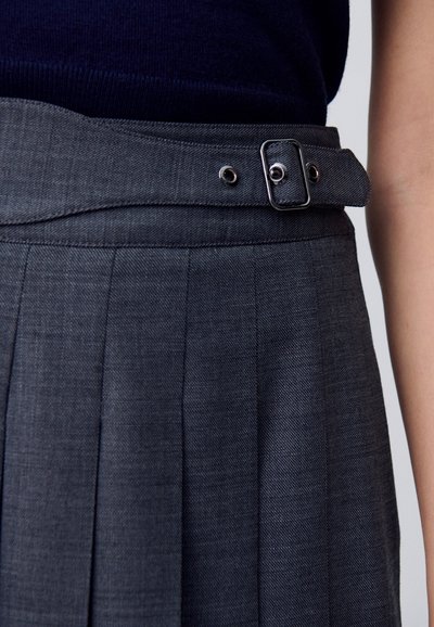 Falda gris plisada con una cinturilla ancha, que presenta un cinturón con una hebilla rectangular y detalles de ojales. Tejido suave y texturizado.