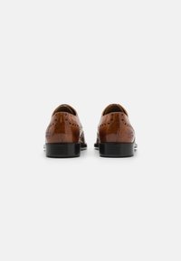 Scarpe da uomo in pelle marrone con punta rotonda, dettagli brogue e suola in gomma nera. Superficie liscia con una leggera lucentezza.