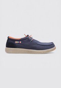 Zapatos de lona azul marino con punta redondeada, suela de goma texturizada beige, forro interior naranja y cordones grises. Presenta detalles de acento en color.