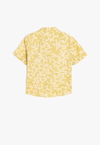 Camisa de manga corta de tejido amarillo con un patrón abstracto en zigzag blanco. Diseño casual con un ajuste relajado y detalle en el cuello.