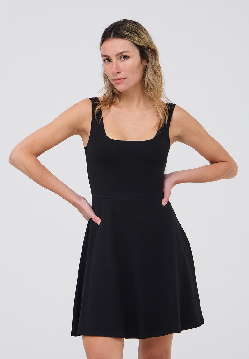 Abito nero con scollatura quadrata, design senza maniche e gonna svasata. Il tessuto è morbido e liscio, con spalline testurizzate vicino alle spalle.