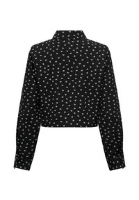 Chemisier noir à manches longues et coupe courte avec un petit motif floral blanc, poignets à bouton, et col pointu, vu de dos.