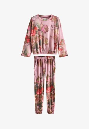 Dvoudílná květovaná souprava na doma světle růžové barvy. Skládá se z dlouhého rukávu a kalhot s elastickým pasem, oboje zdobené vzory vícero barevných květin.