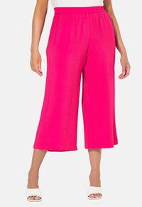 Fuchsia, wijde culottes met een elastische tailleband, gemaakt van lichtgewicht, gestructureerde stof. Kenmerken zijn de korte lengte, gecombineerd met witte schoenen.
