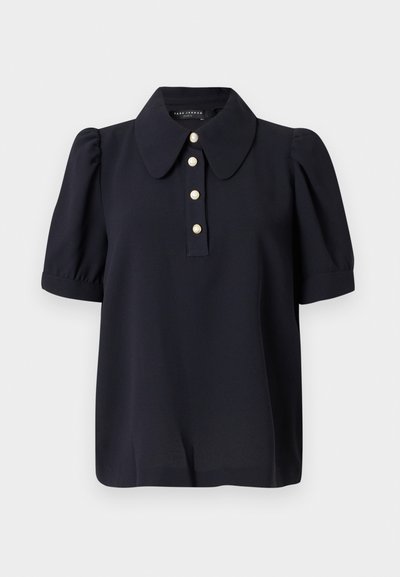 Marineblå bluse med en stor krave, korte puffærmer og fem perle-lignende knapper foran. Lavet af glat stof.