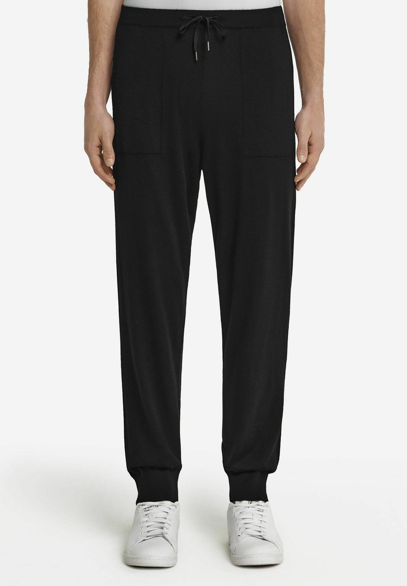 Czarne spodnie dresowe z elastycznym paskiem, dwoma bocznymi kieszeniami, zwężanymi nogawkami i ściągaczami, wykonane z miękkiego, teksturowanego materiału.